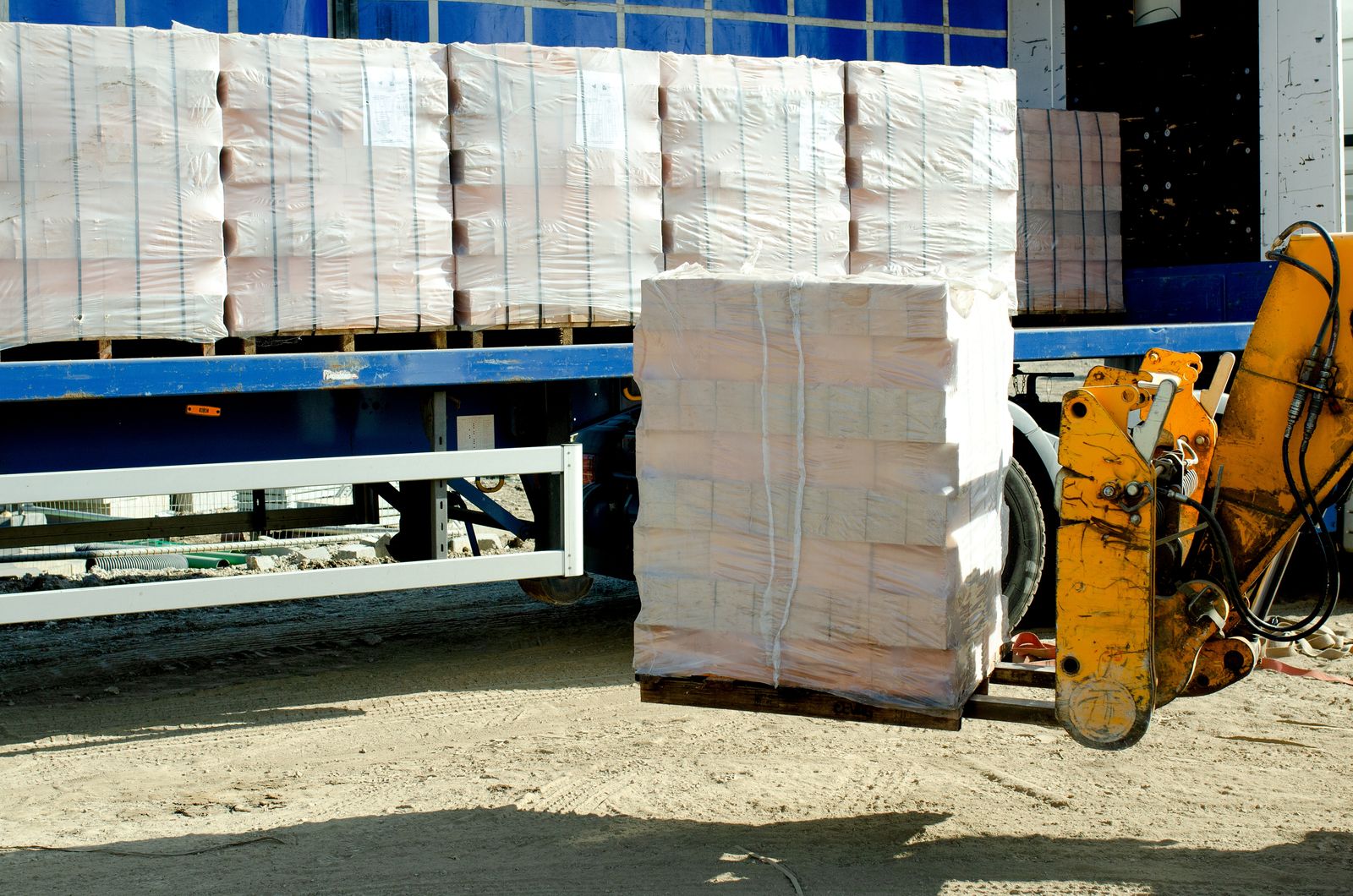 Forklift unloading a wrapped pallet from a lorry